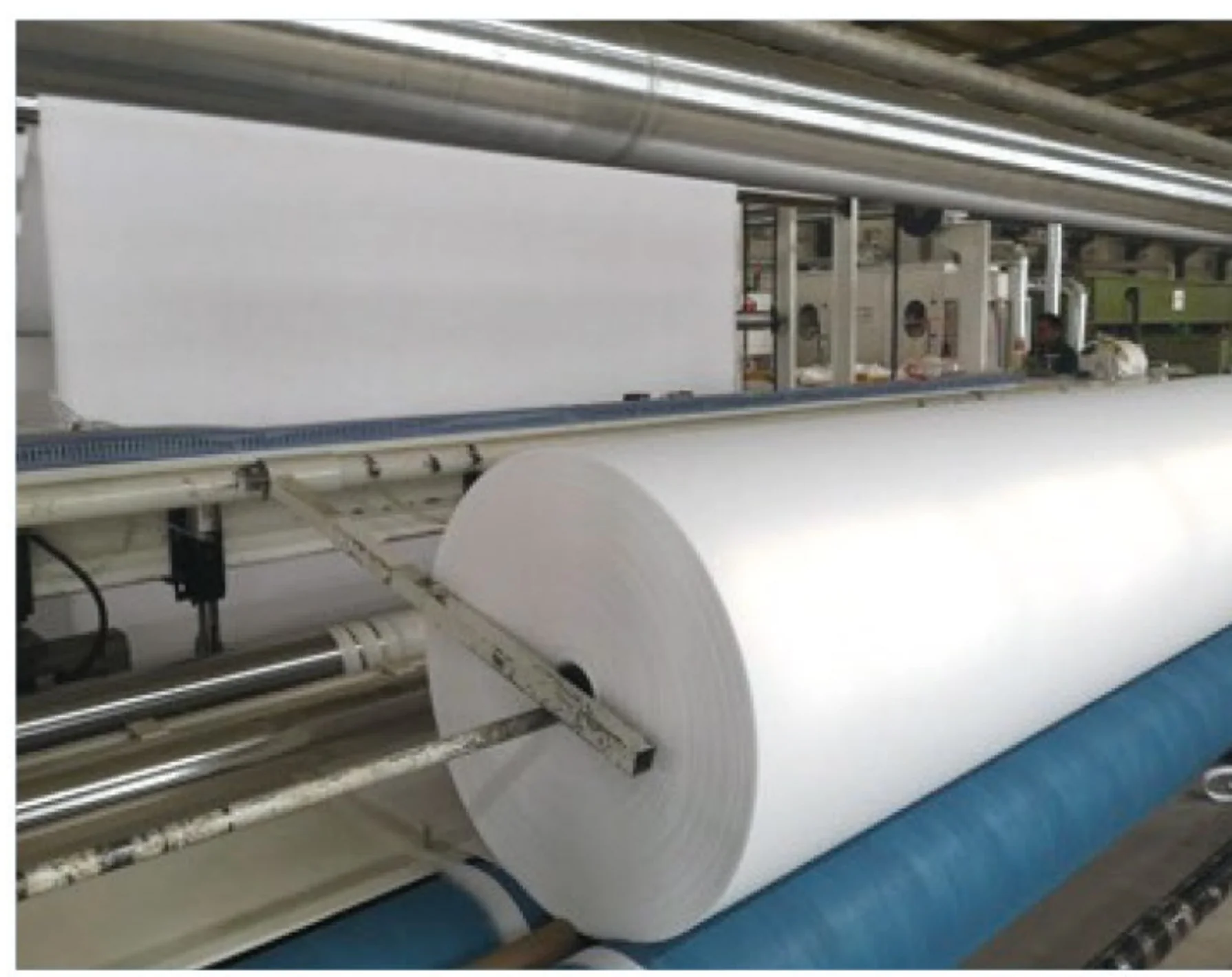 White nonwoven geotextile roll shown on production equipment